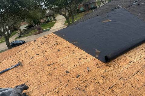 Roof section stripped down to bare wood decking with underlayment partly rolled out