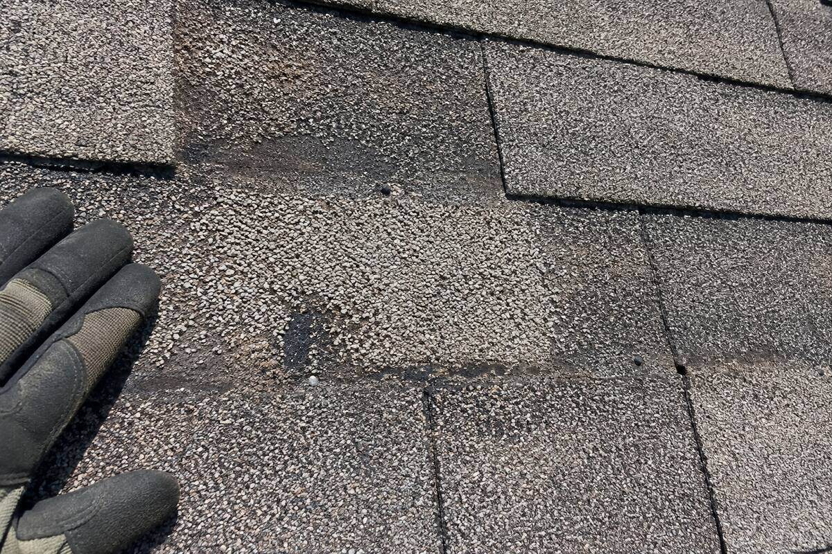 Close-up of a shingle surface with the granules worn thin and the mat showing through